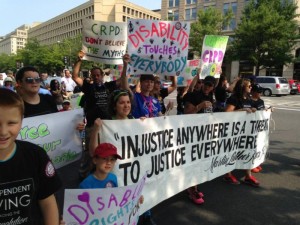 Advocates rally for ratification of the CRPD in the 2014 NCIL March to Capitol Hill. Signs include: Ratify CRPD Now; CRPD – Don’t Believe the Myths; Disability Touches Everybody; Free Our People; Disability Rights for My Sister; and NCIL’s Banner: “Injustice Anywhere Is A Threat to Justice Everywhere” – Martin Luther King, Jr.