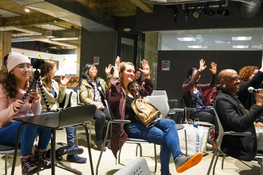 LINK20 members sitting in a room and applauding using American Sign Language