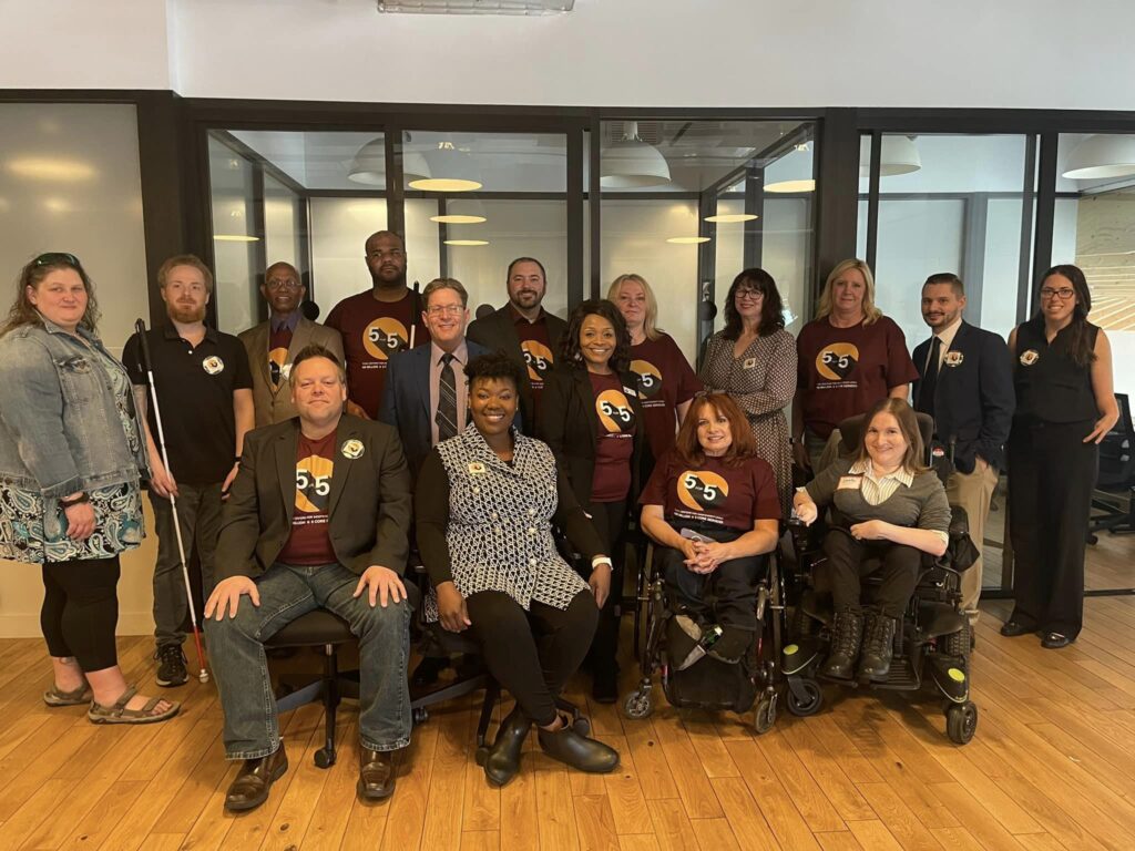 Image: sixteen advocates pose for a group photo. Several are wearing shirts with the 5 for 5 Logo.